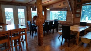 A wooden interior with a large central column, dining tables, and chairs. - Northern Sky Lodge (Fairbanks)