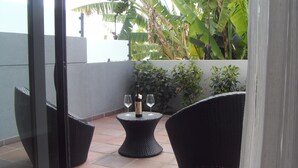 Ein Balkon mit Korbmöbeln, einer Weinflasche und zwei Gläsern.