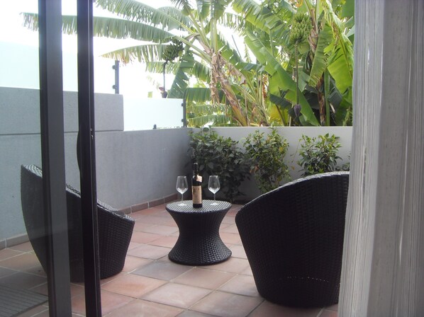 A balcony with wicker furniture, a bottle of wine, and two glasses.