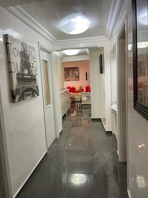 A hallway with a polished floor, a painting of the Eiffel Tower, and a red sofa in the background. - Super apartment in the heart of downtown CASABLANCA (Casablanca)