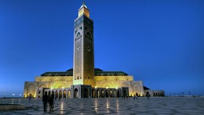 Een groot, verlicht gebouw met een opvallende toren en meerdere bogen.