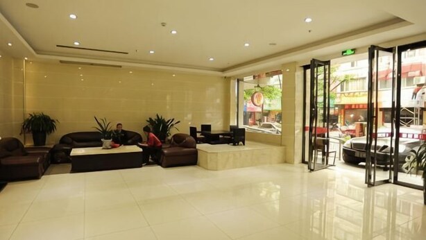 A hotel lobby with a reception desk, seating area, and large windows offering a view of the street. - Cang Long Hotel (Hezhou)