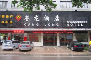 Un hotel con un cartel llamativo, un estacionamiento con varios coches y una fachada con señalización visible.