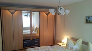 Ein Schlafzimmer mit einem Bett, einem Nachttisch, einer Lampe, einem Kleiderschrank und einem Spiegel.