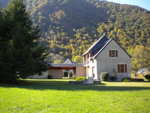Une maison à deux étages, dotée d’un toit en pente, d’un balcon et d’une pelouse bien entretenue à l’avant.