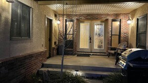 A residential building with a brick facade, a front porch, and a barbecue grill.