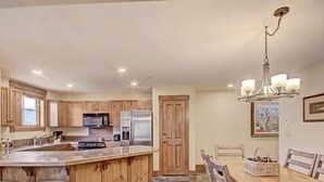 Eine Küche mit Holzausstattung, Edelstahlgeräten und einem Essbereich mit Holztisch und -stühlen.