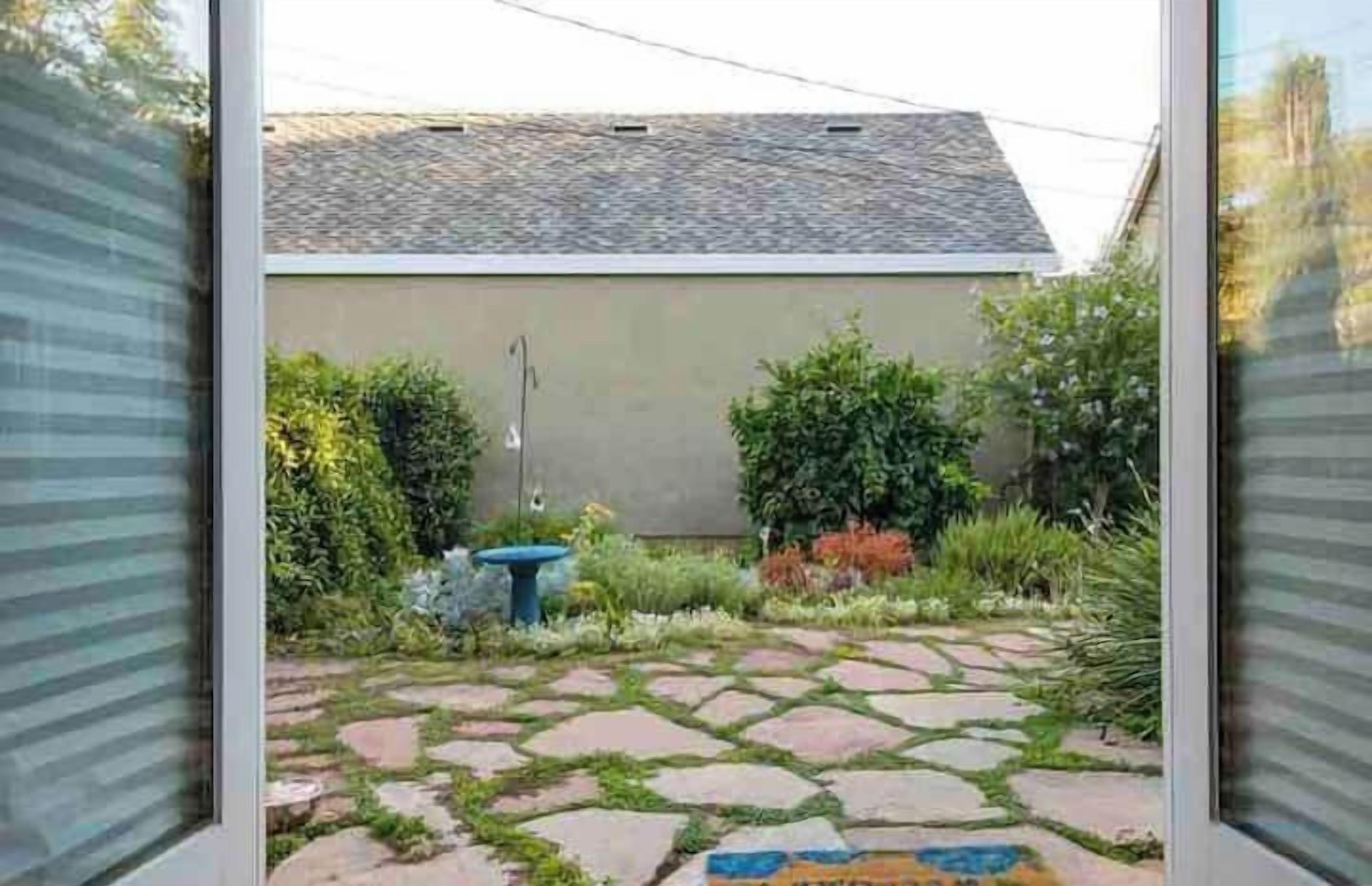A garden with a stone pathway leading to a building with a sloped roof.