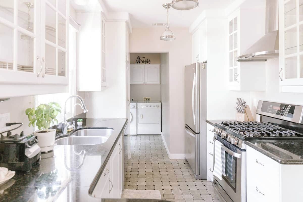 A modern kitchen with white cabinetry, a stainless steel refrigerator, a gas stove, and a dishwasher.