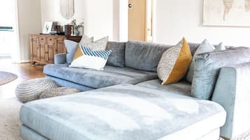 A modern living room with a grey sectional sofa, a wooden cabinet, and a world map on the wall.