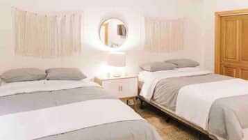 Un dormitorio con dos camas, una mesita de noche, un espejo y una puerta de madera.