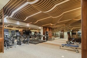 A gym with exercise equipment, a wooden ceiling design, and a mirrored wall. - Jiazhou Ligang Hotel (SECTION 4 OF BINJIANG MIDDLE R)