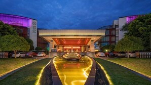 Ein Hotel mit Eingangsbereich, Wasserspiel, überdachtem Gang und moderner Fassade.