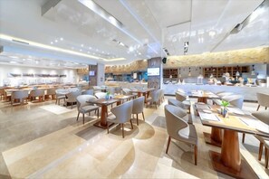 A spacious restaurant with multiple dining tables and chairs, a bar area, and a modern ceiling design.