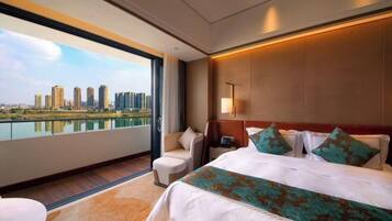 A modern hotel room with a large bed, a desk, and a view of a city skyline.