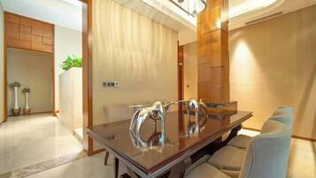 A modern dining area with a glass-top table, cushioned chairs, and a wooden accent wall.