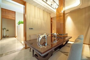Un espace repas moderne avec une table à plateau en verre, des chaises rembourrées et un mur décoratif en bois.
