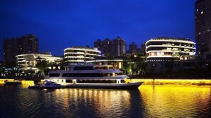 Een hotel aan het water met meerdere balkons en een boot afgemeerd in de buurt.