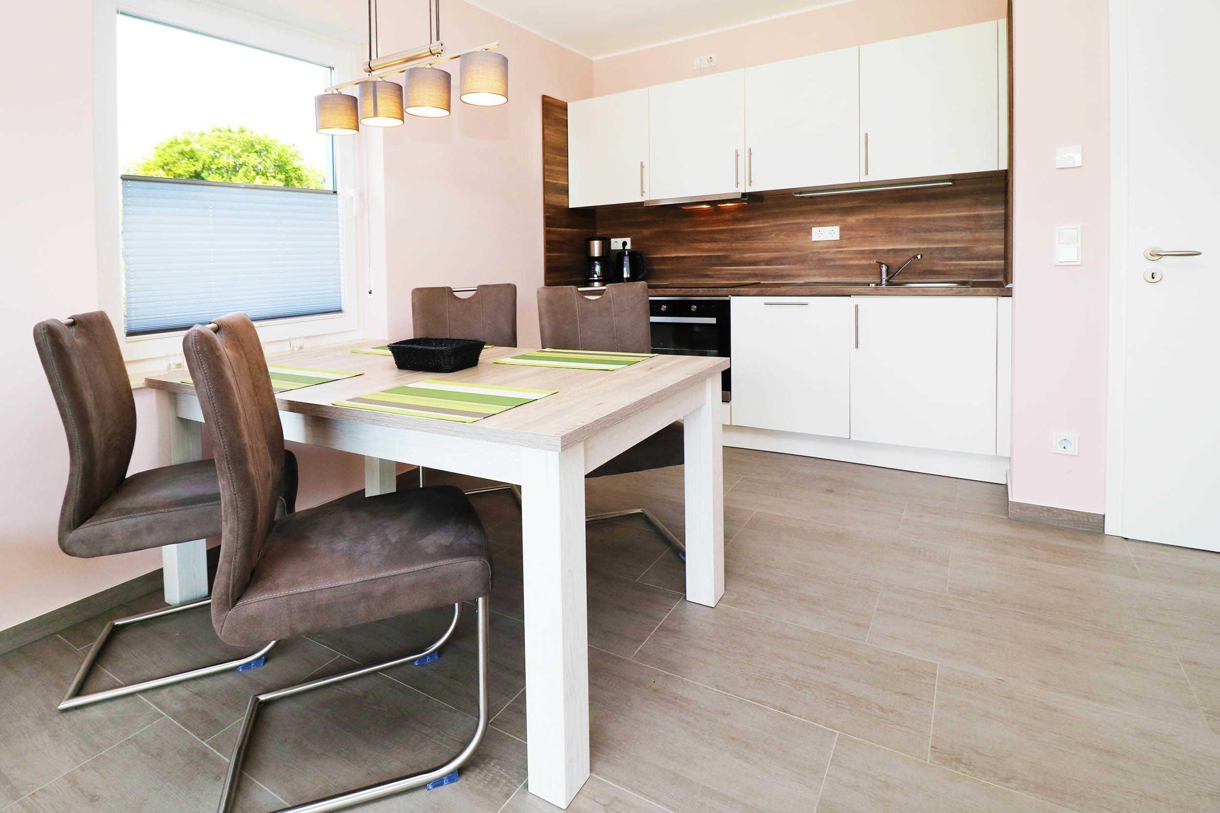 A modern kitchen with white cabinets, a wooden countertop, and a dining area with a table and chairs.