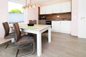 Une cuisine moderne avec des meubles blancs, un plan de travail en bois et un coin repas comprenant une table et des chaises.