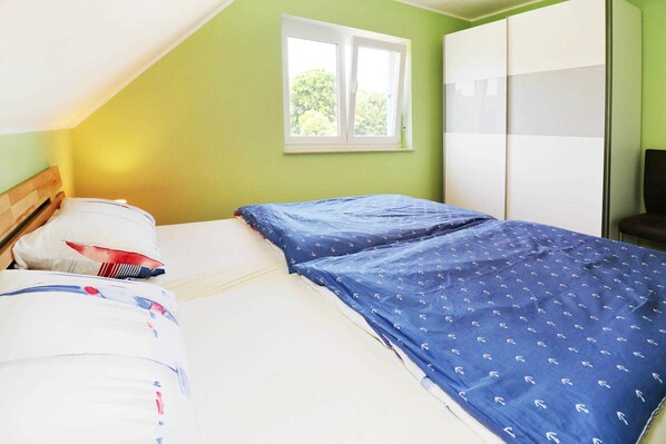 A bedroom with a single bed, a window, and a wardrobe.