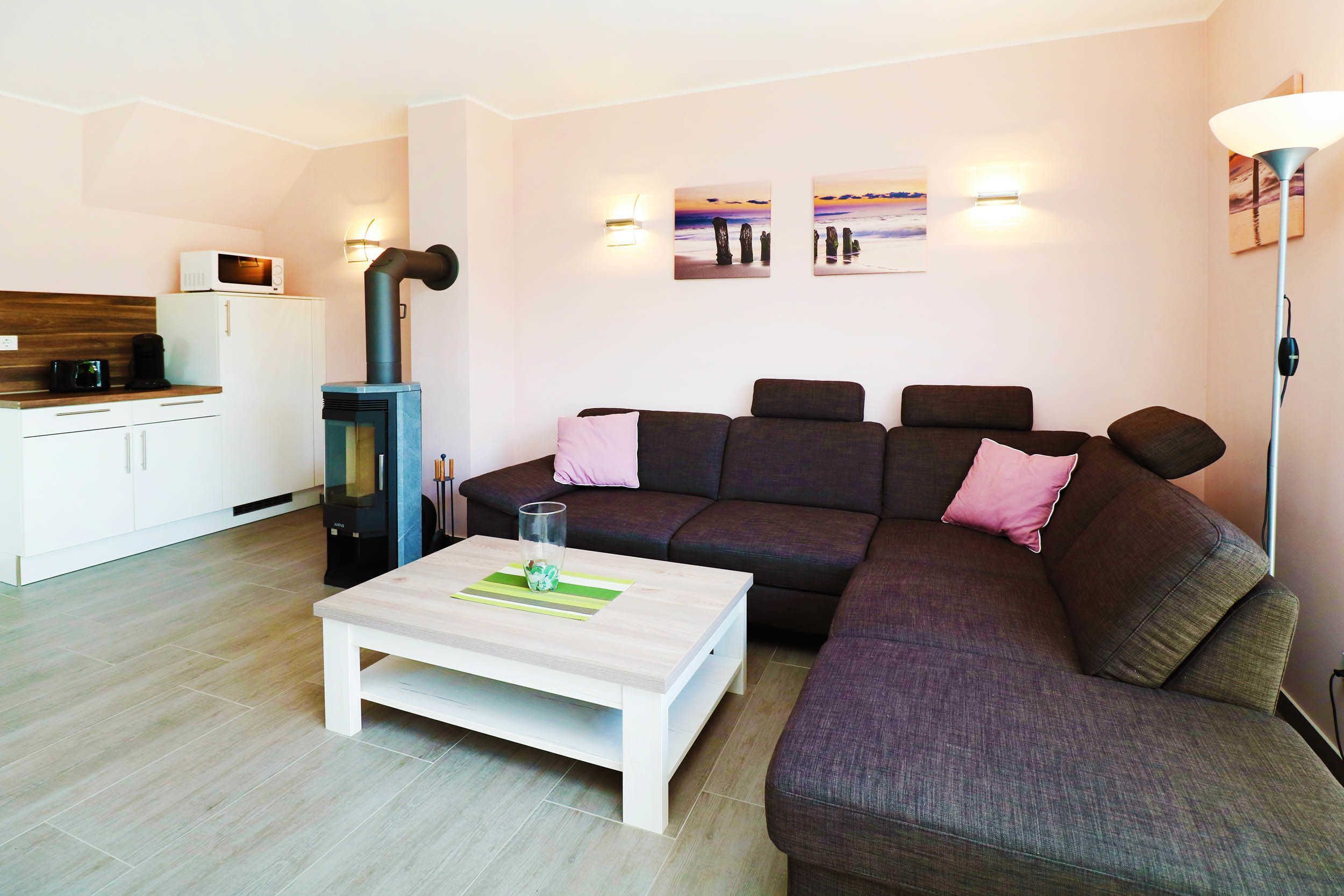 A modern living room with a sofa, a coffee table, a kitchen area with a microwave, and a fireplace.