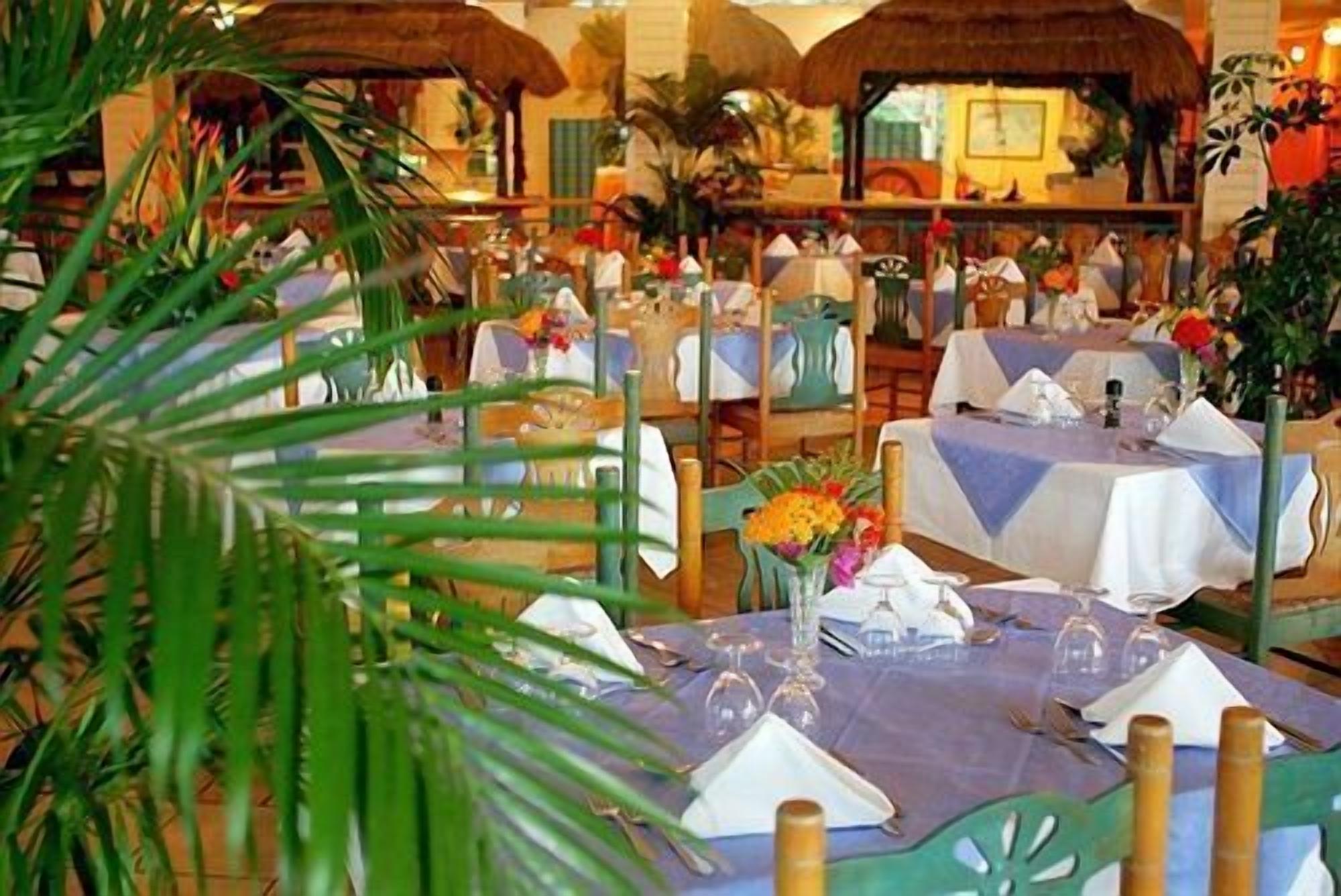 A restaurant with multiple tables set for dining, some with flowers and wine glasses.