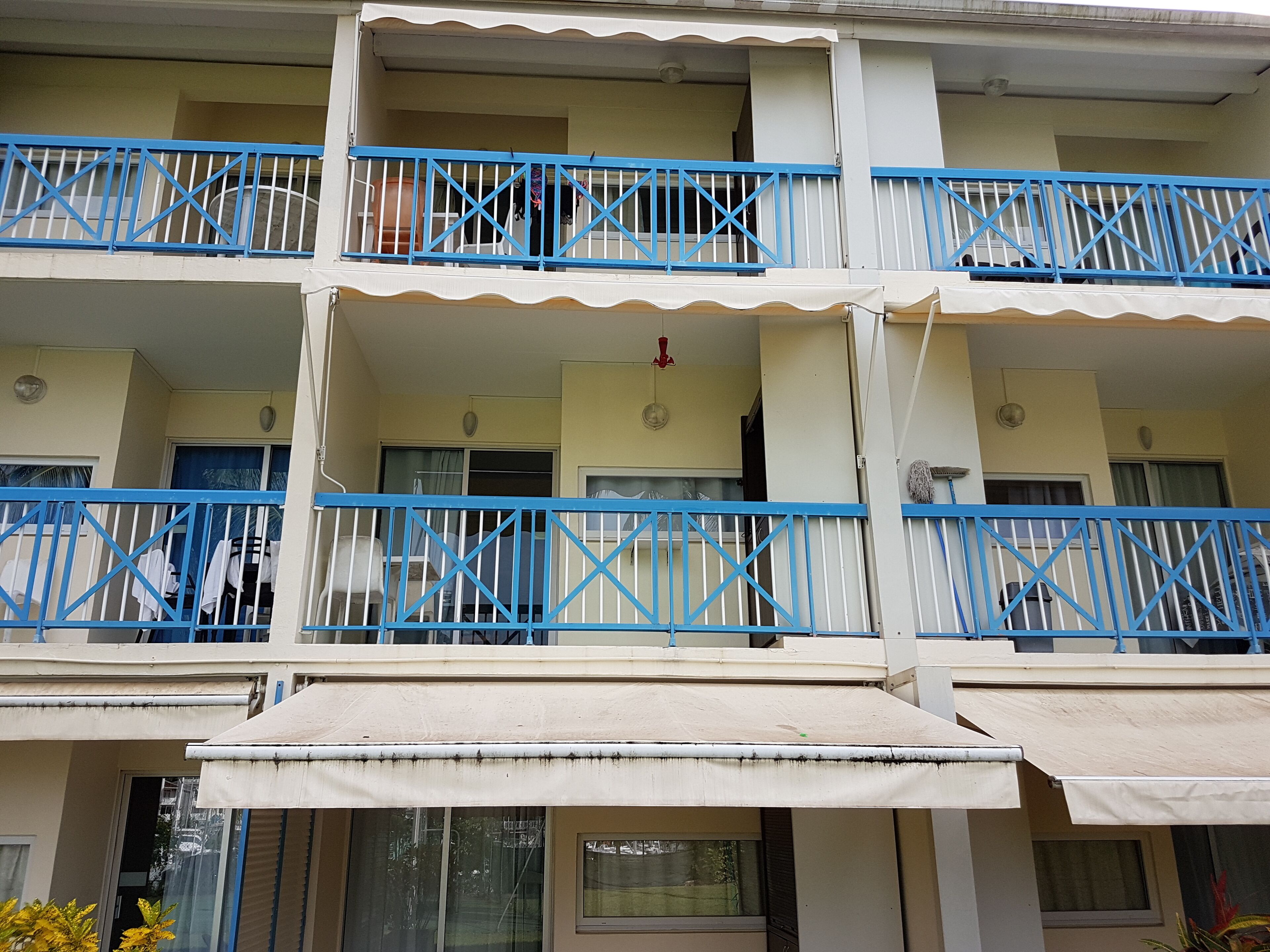 Un edificio de varios pisos con balcones, cada uno con barandas y toldos azules.