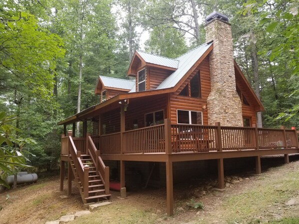 A cabin with a stone chimney, wooden deck, and a staircase leading to the entrance. - Kays Kabin Appalachian Trail (Suches)