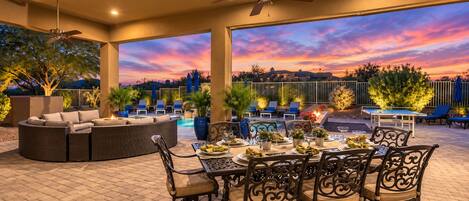 An outdoor patio with a dining table set for four, surrounded by wicker furniture and metal chairs.
