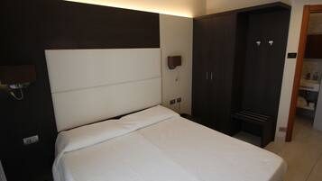 Una habitación de hotel con una cama, un armario y una lámpara fijada a la pared.