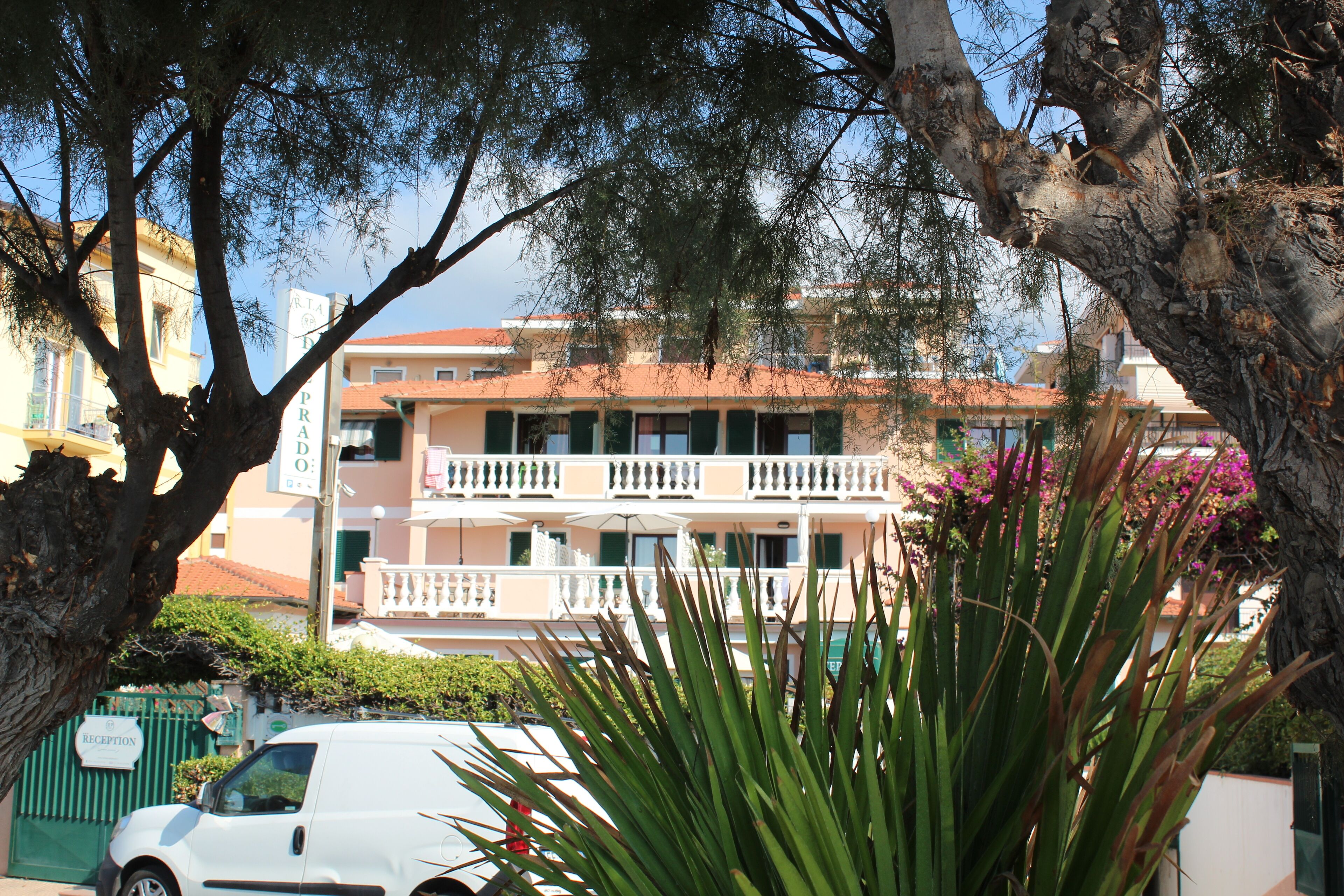 A building with a balcony, a reception sign, and a car parked in front.