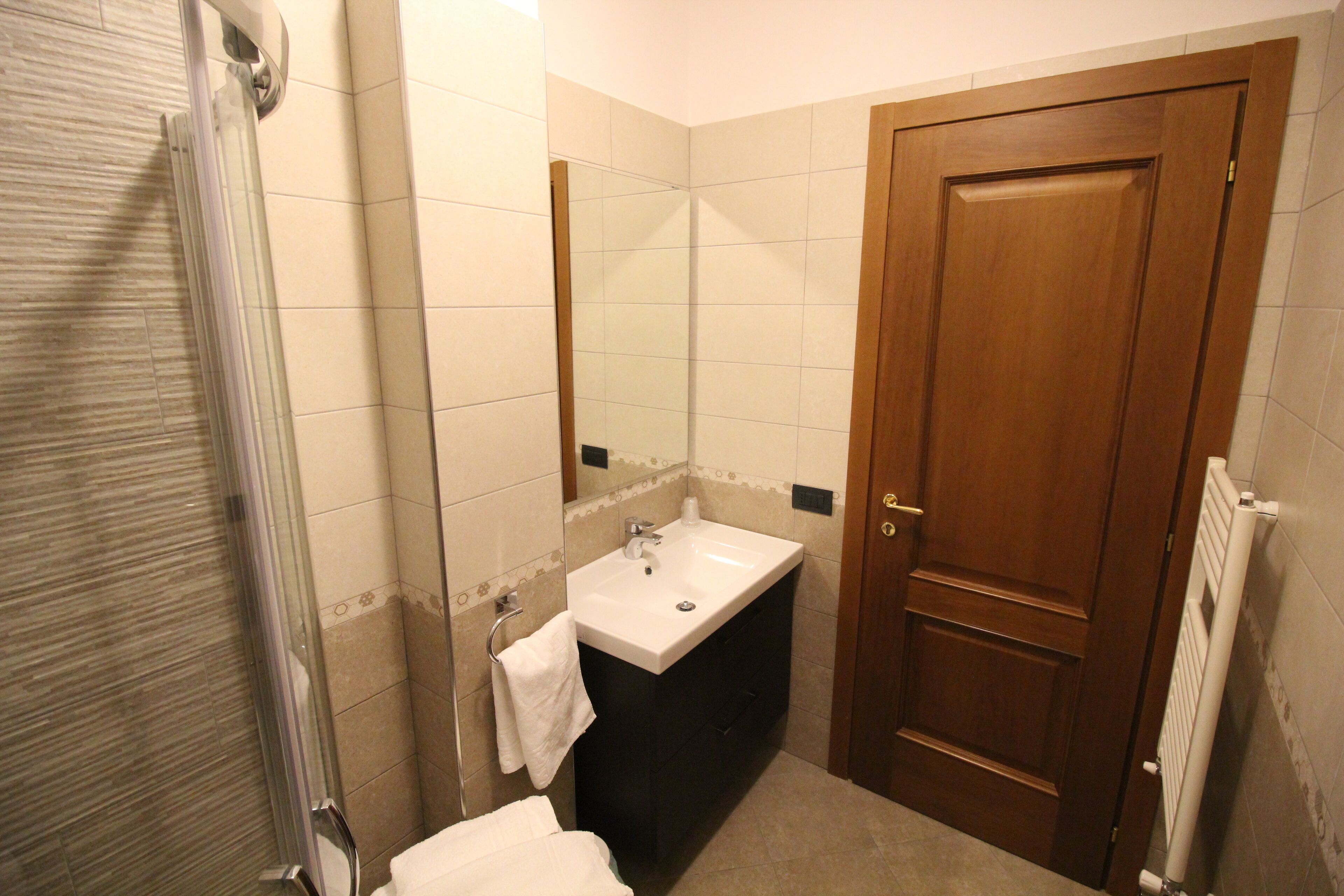 A bathroom with a shower, sink, and a wooden door.