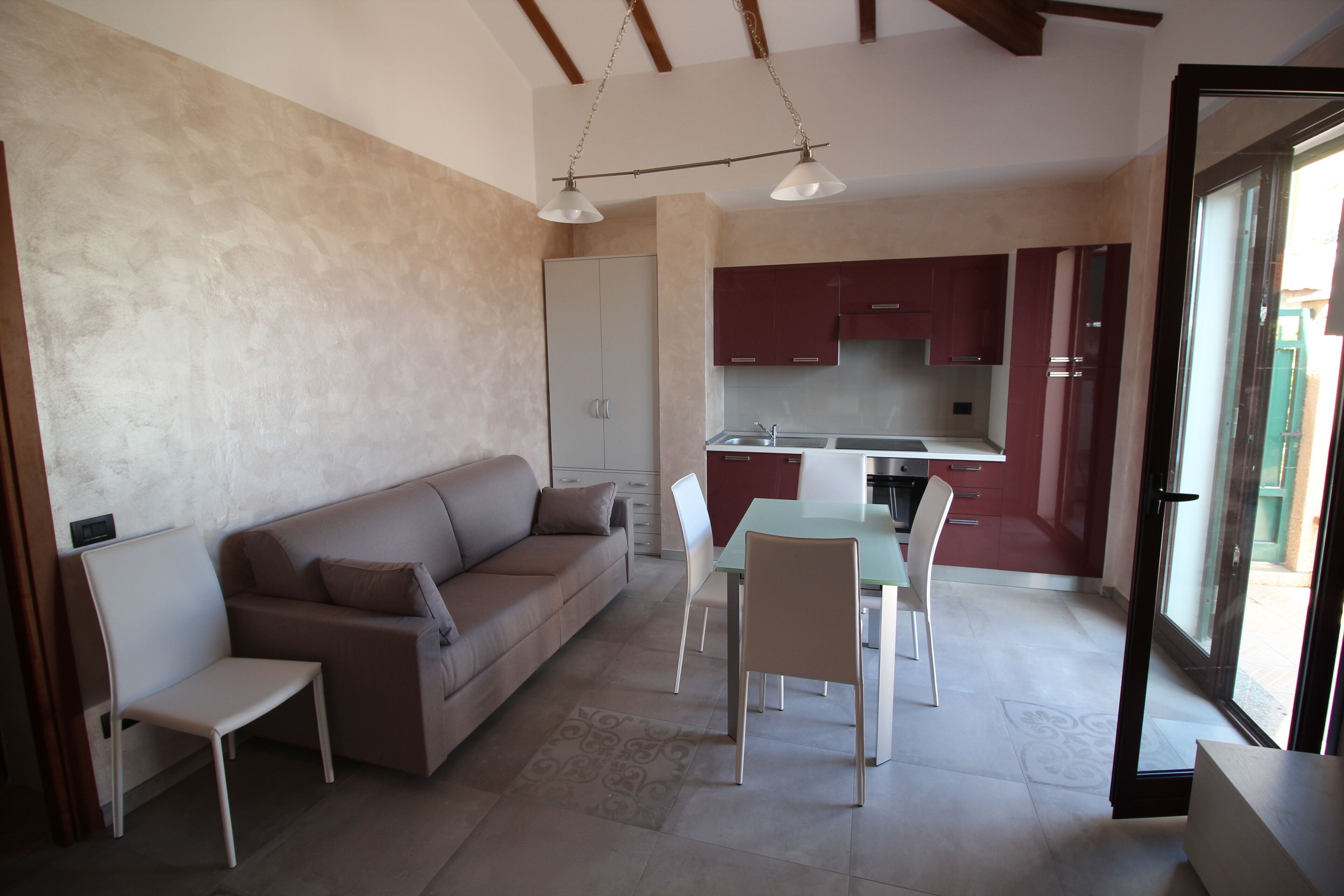 Una sala de estar moderna con un sofá, sillas, una mesa de comedor y una zona de cocina con armarios y un lavabo.