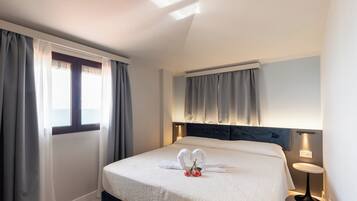 A hotel room with a bed, curtains, a bedside table, and a nightstand.