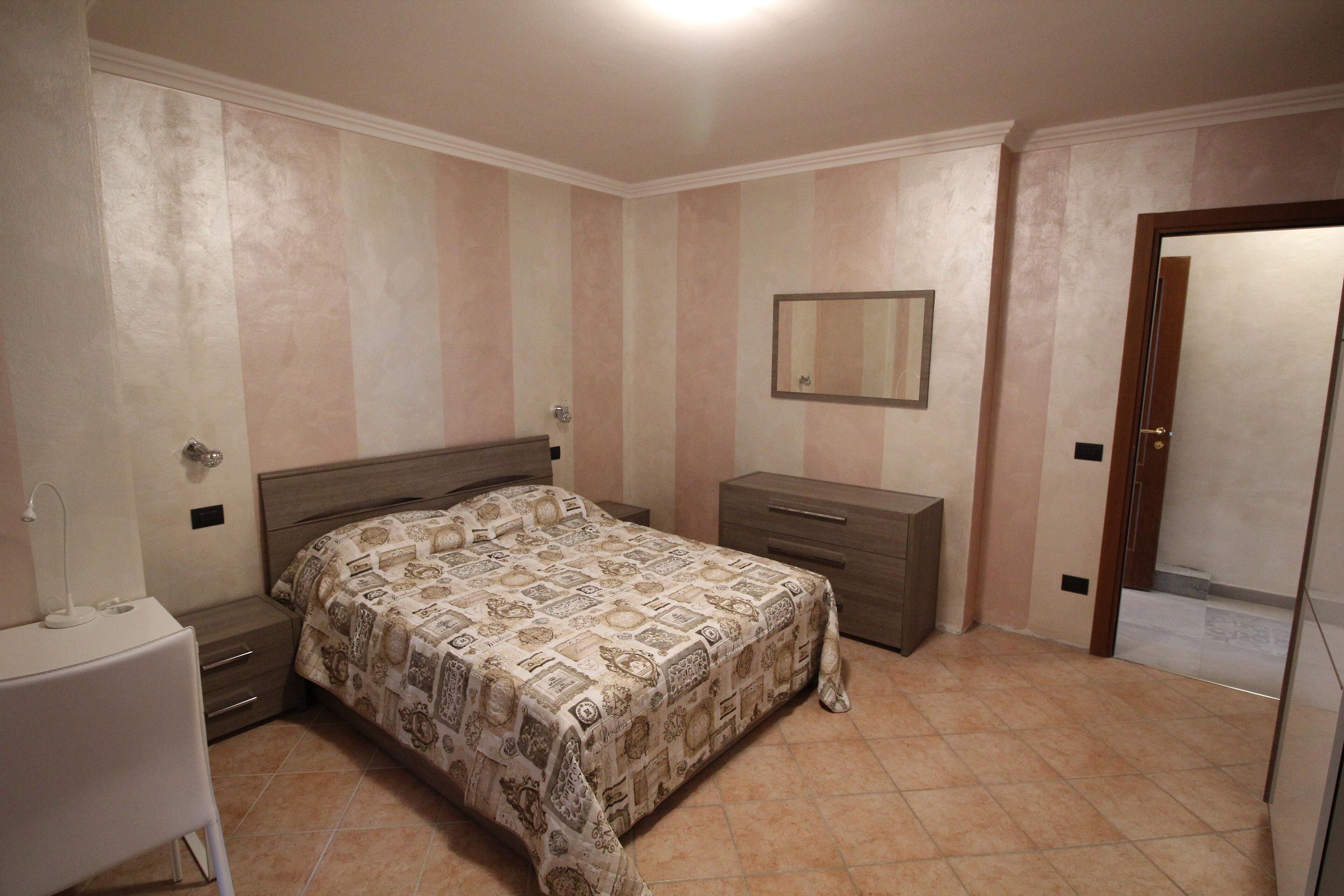 A bedroom with a bed, bedside table, and a dresser.
