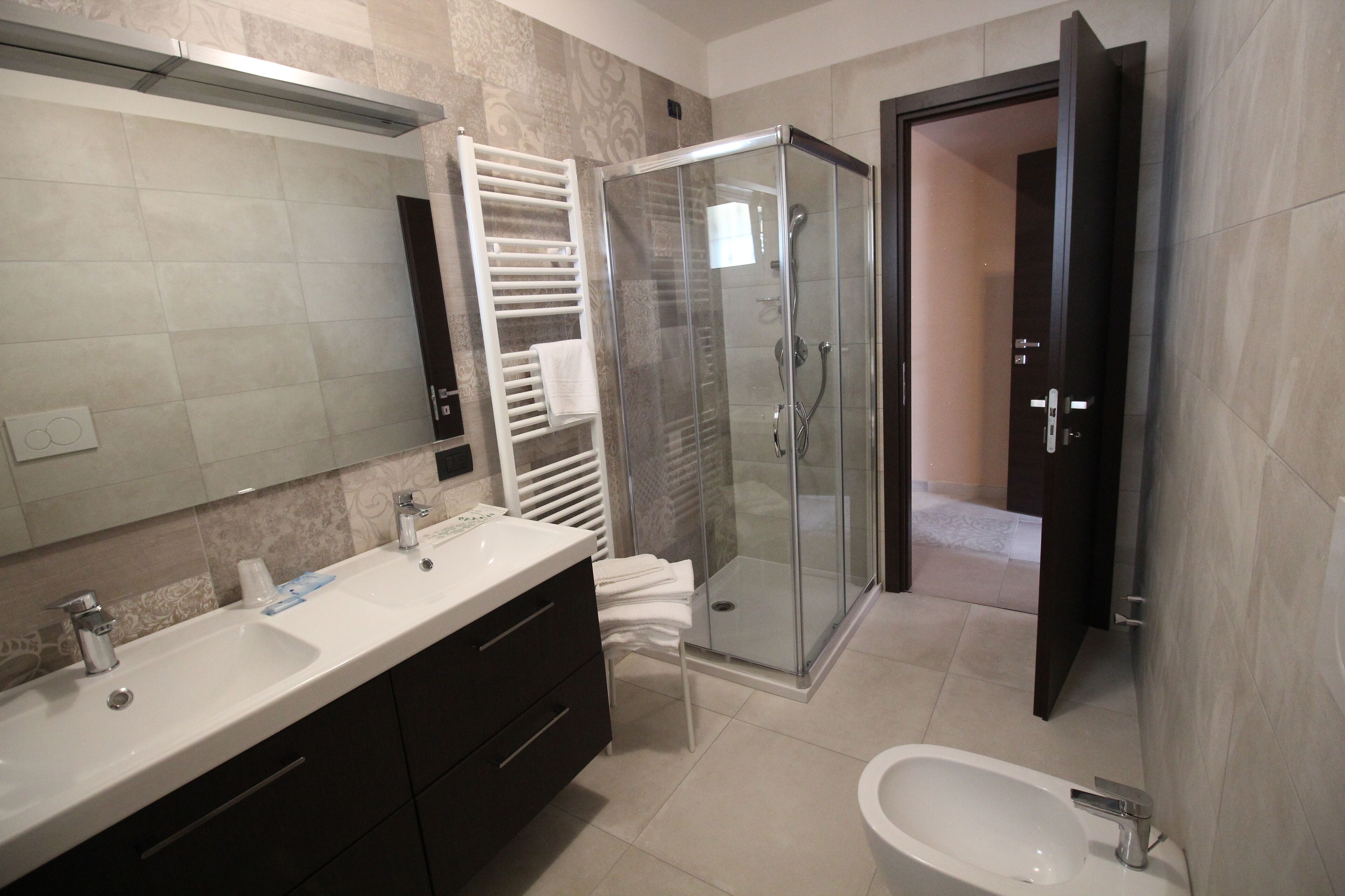 A modern bathroom with a glass-enclosed shower, a large mirror, a double sink vanity, and a separate bathtub.