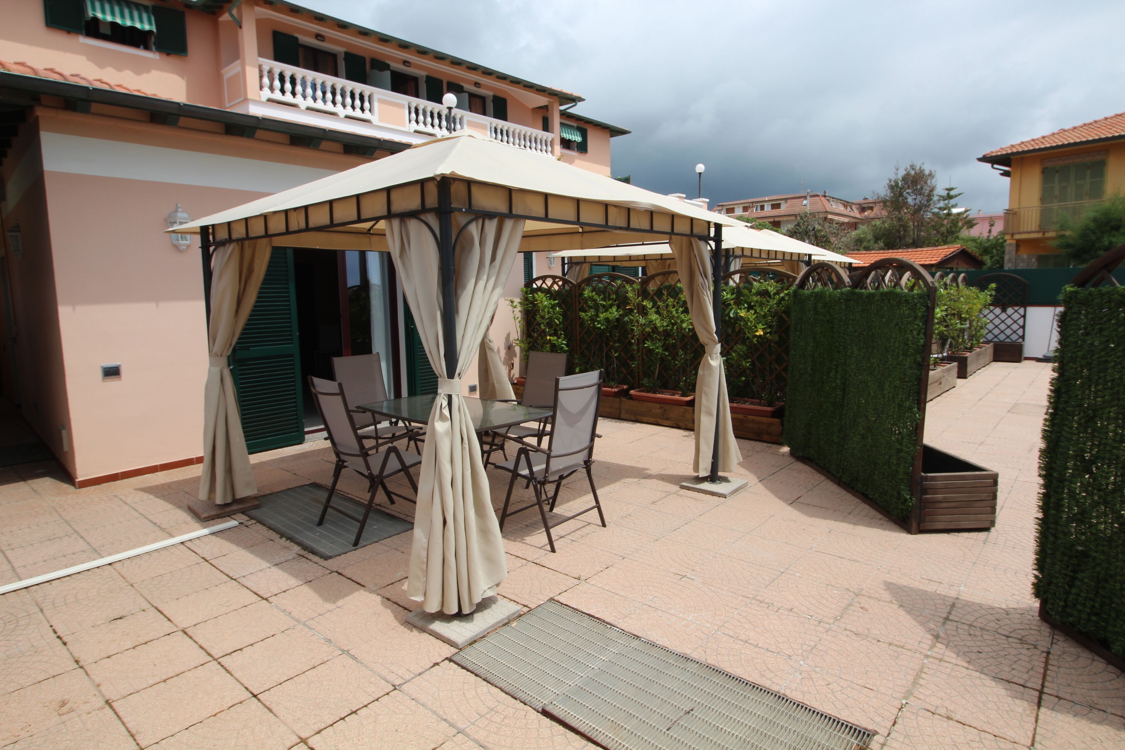 Eine Terrasse mit überdachter Sitzgruppe, einem Tisch und Stühlen.