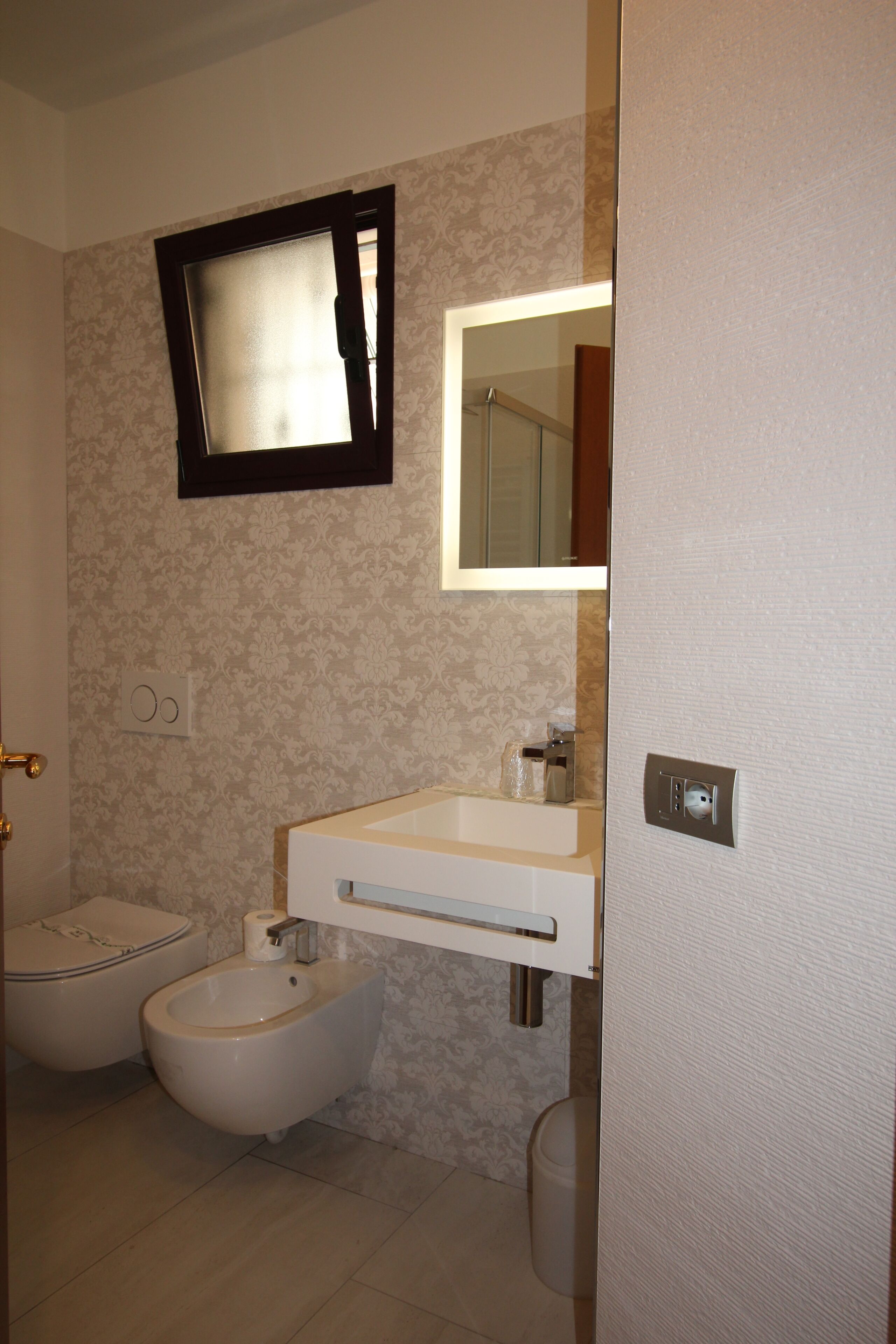 Un baño con inodoro, bidé, lavabo y espejo.