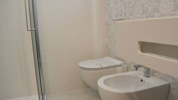 Un baño con inodoro, bidé y zona de ducha.