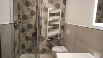 Une salle de bain avec douche, toilettes et lavabo.