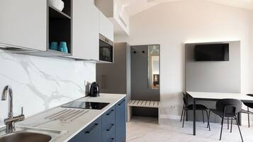 A modern kitchen with a marble countertop, a built-in oven, and a coffee maker.