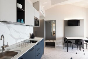 Cozinha moderna com bancada de mármore, forno embutido e máquina de café.