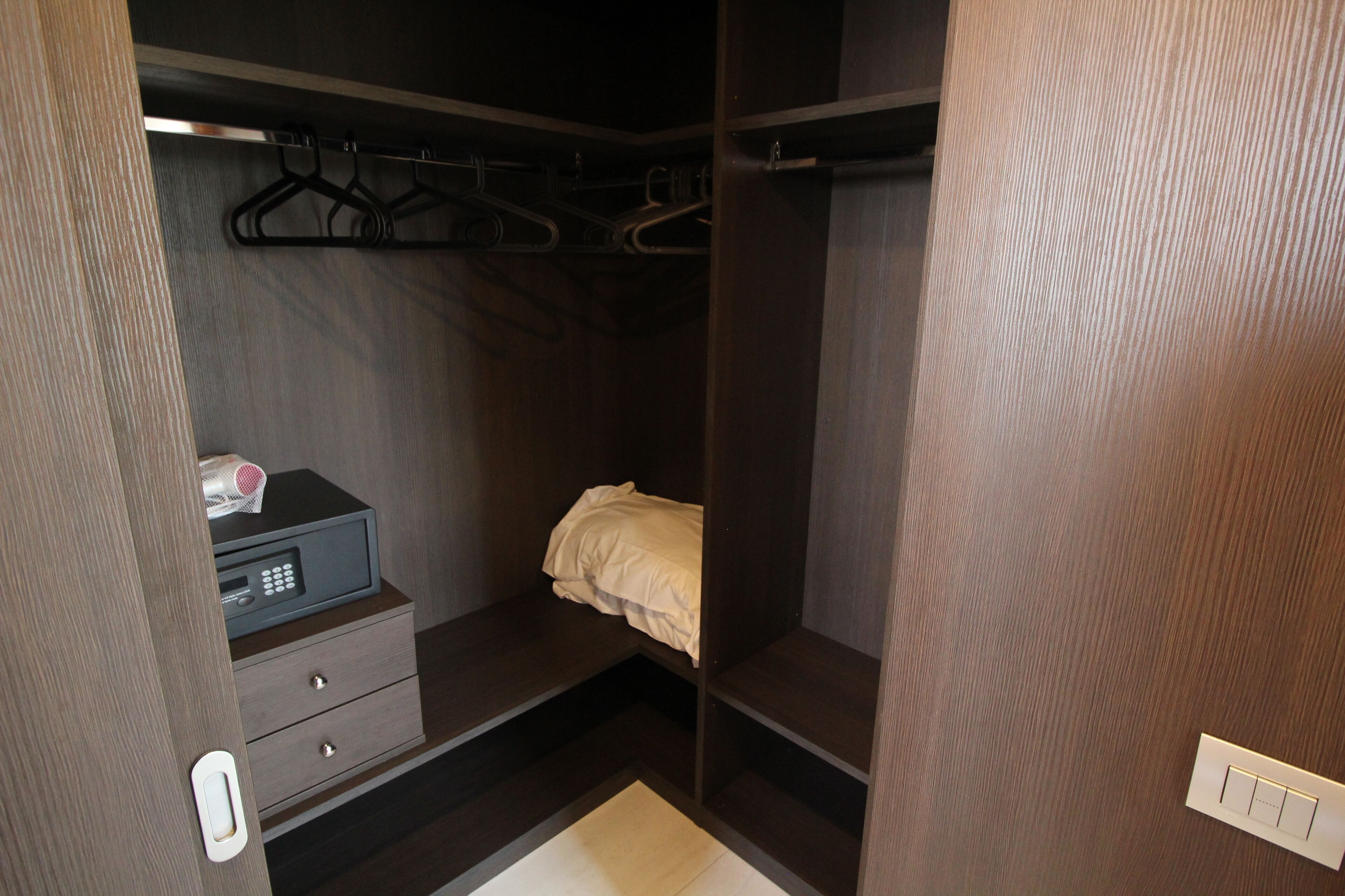 A compact walk-in closet with a bed, a small desk, and a hanging rack.