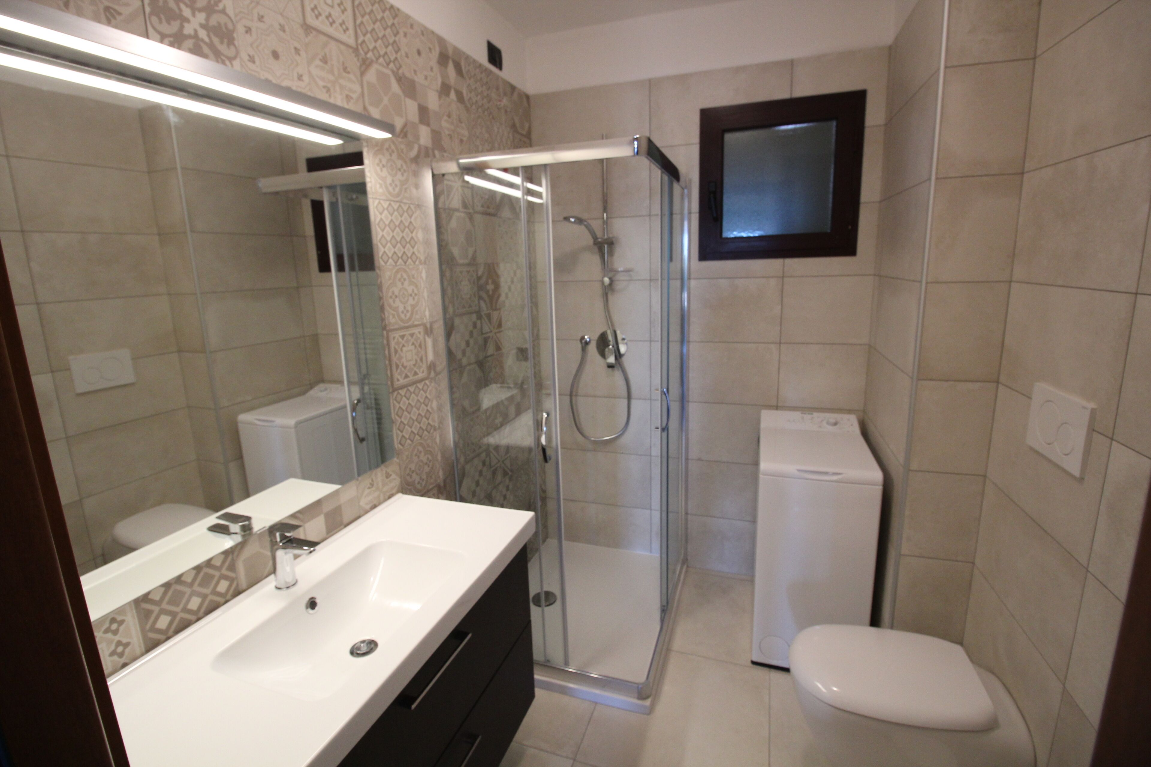 A modern bathroom with a glass-enclosed shower, a white sink, and a toilet.