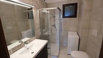 A modern bathroom with a glass-enclosed shower, a white sink, and a toilet.