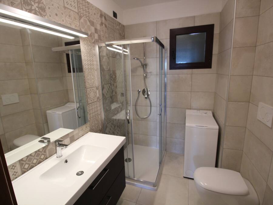A modern bathroom with a glass-enclosed shower, a white sink, and a toilet.