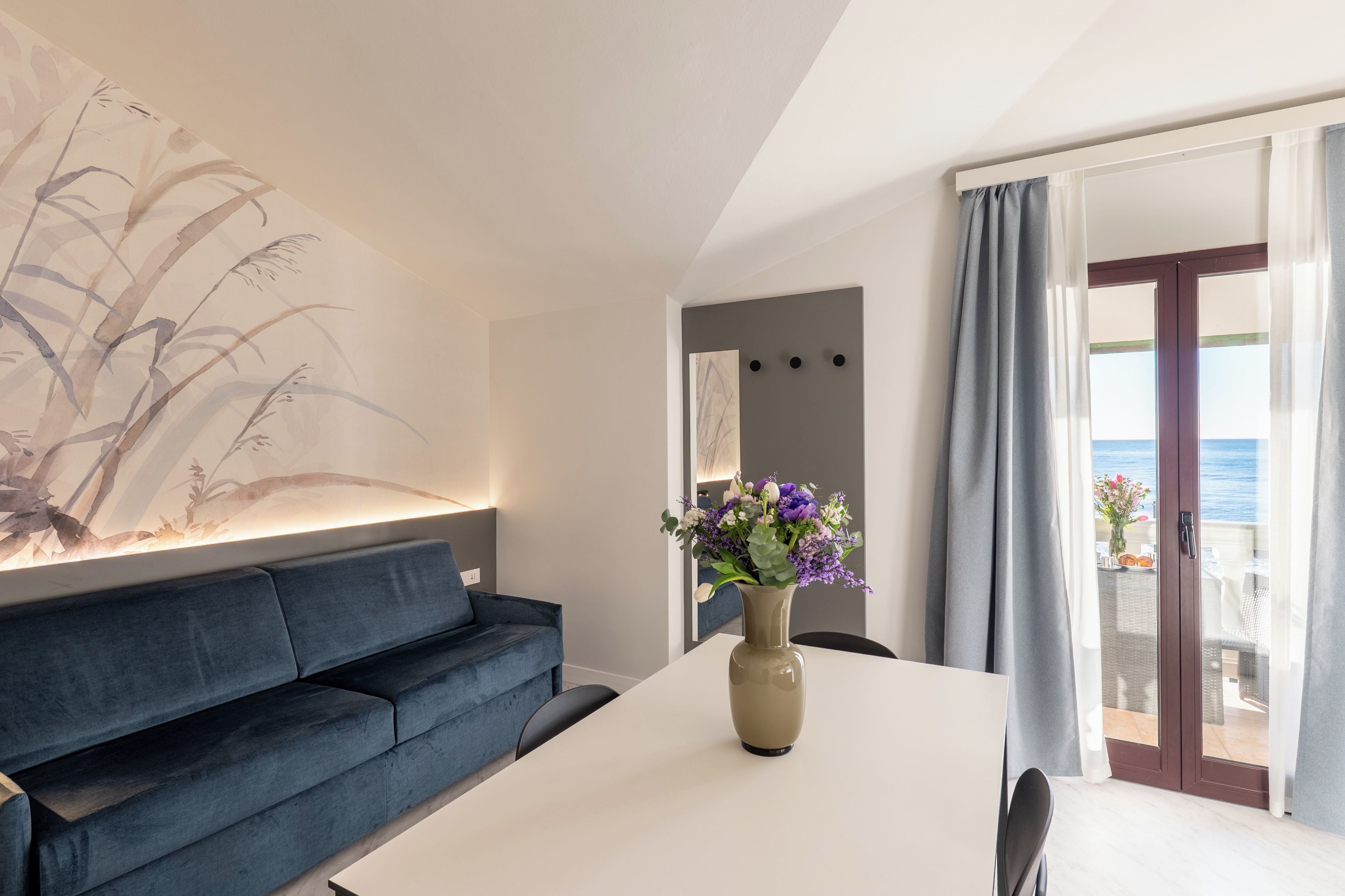 A modern living room with a sofa, a table, and a vase of flowers.