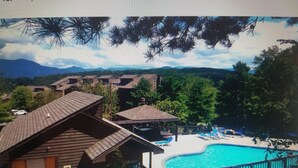 A resort with multiple buildings, a swimming pool, and a mountainous backdrop. - "AMAZING" LONG RANGE MOUNTAIN VEIWS!! Peaceful MountainTop Getaway! (Gatlinburg)