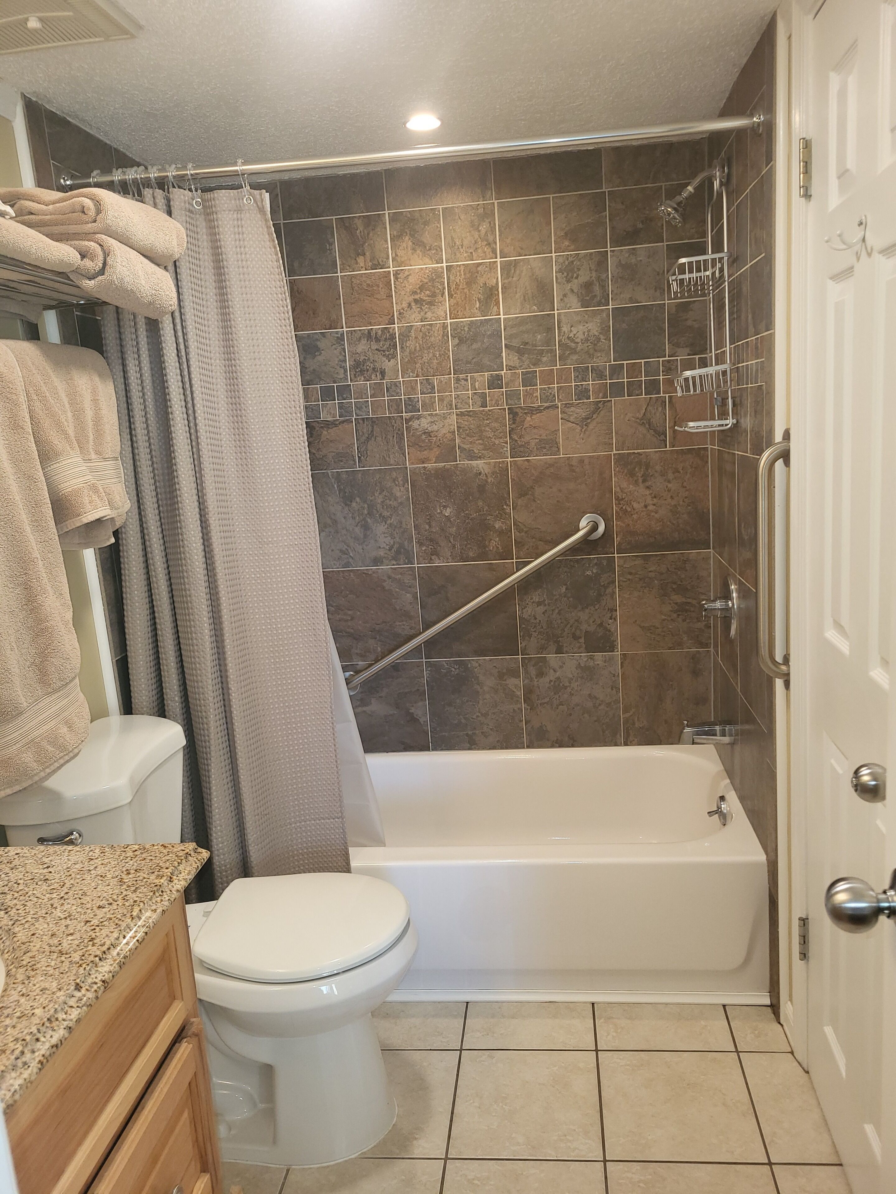 Un baño con ducha, inodoro y encimera de granito.